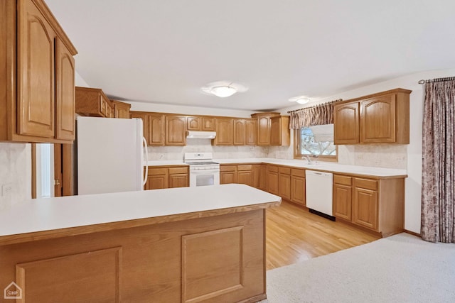 kitchen with white appliances, sink, kitchen peninsula, and light hardwood / wood-style floors