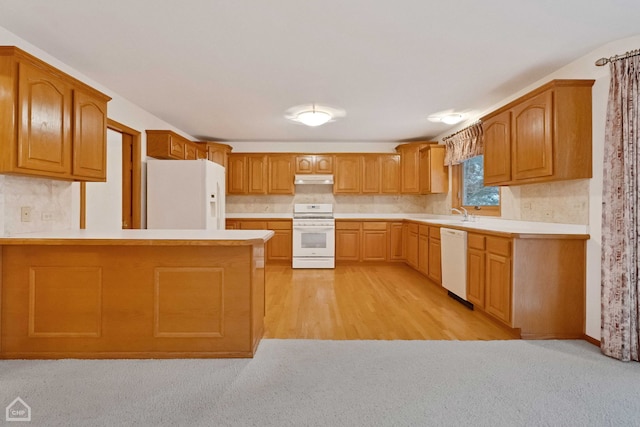 kitchen with sink, kitchen peninsula, white appliances, and light hardwood / wood-style flooring