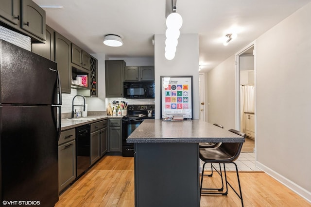 kitchen featuring pendant lighting, sink, a center island, black appliances, and a kitchen bar