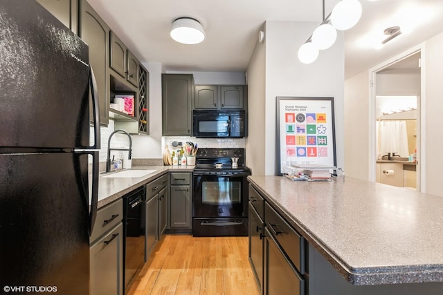 kitchen with decorative light fixtures, tasteful backsplash, sink, black appliances, and light hardwood / wood-style flooring