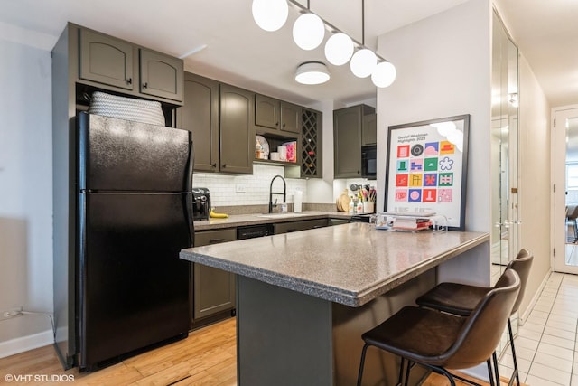 kitchen featuring a breakfast bar, sink, backsplash, hanging light fixtures, and black appliances