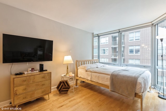 bedroom with a wall of windows and light wood-type flooring