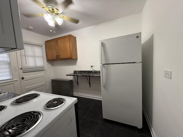 kitchen featuring ceiling fan, white appliances, and dark tile patterned flooring