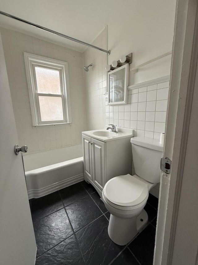 full bathroom with tile walls, vanity, tiled shower / bath combo, and toilet