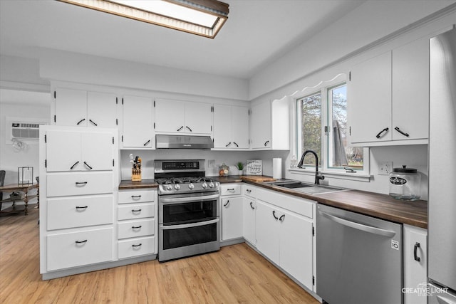 kitchen featuring sink, white cabinetry, light wood-type flooring, a wall unit AC, and stainless steel appliances