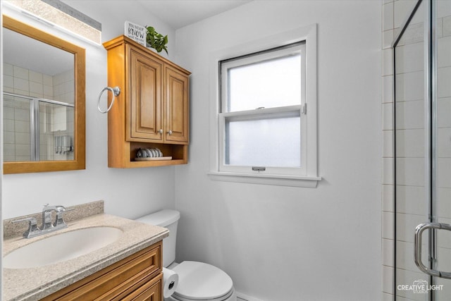 bathroom featuring vanity, a shower with shower door, and toilet