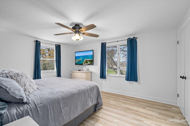 bedroom featuring multiple windows, light hardwood / wood-style floors, and ceiling fan