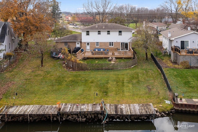 rear view of house with a deck with water view and a lawn