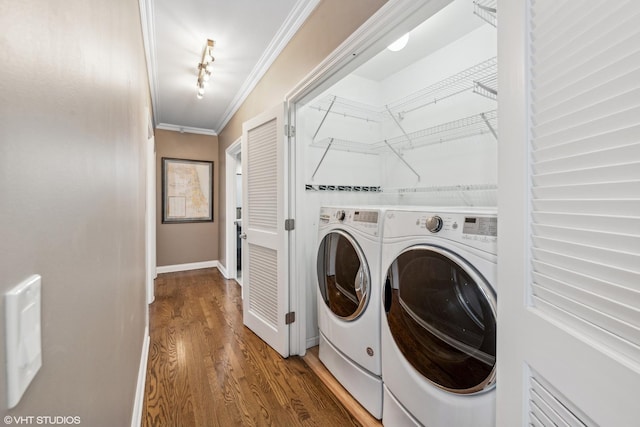 washroom with crown molding, rail lighting, washing machine and dryer, and hardwood / wood-style floors