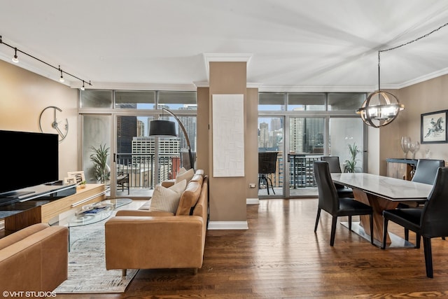 living room featuring dark hardwood / wood-style floors, a wall of windows, a notable chandelier, crown molding, and track lighting