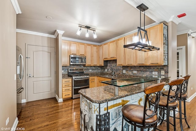 kitchen featuring appliances with stainless steel finishes, a breakfast bar area, dark stone countertops, hanging light fixtures, and kitchen peninsula