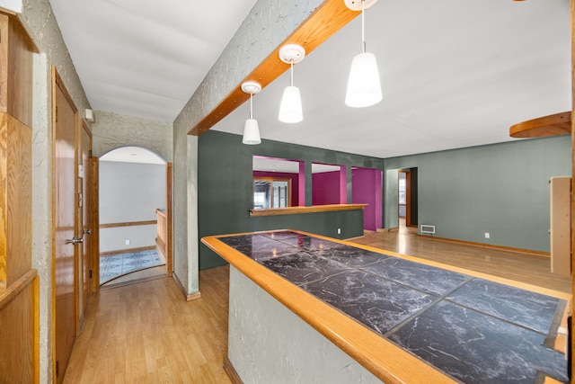 bar featuring hanging light fixtures and light wood-type flooring