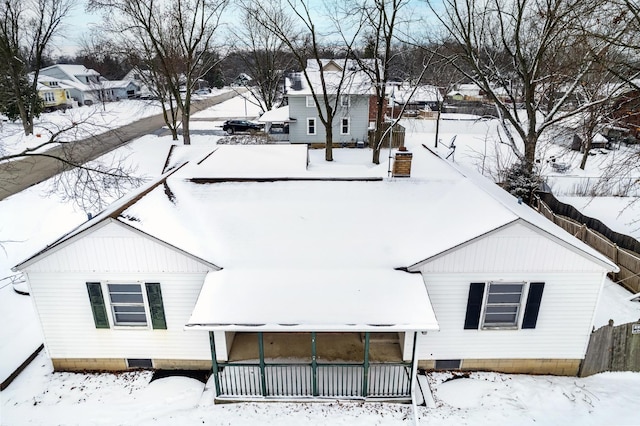 snow covered back of property featuring covered porch