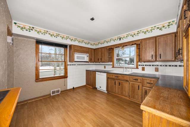 kitchen with sink, white appliances, light hardwood / wood-style flooring, and decorative backsplash