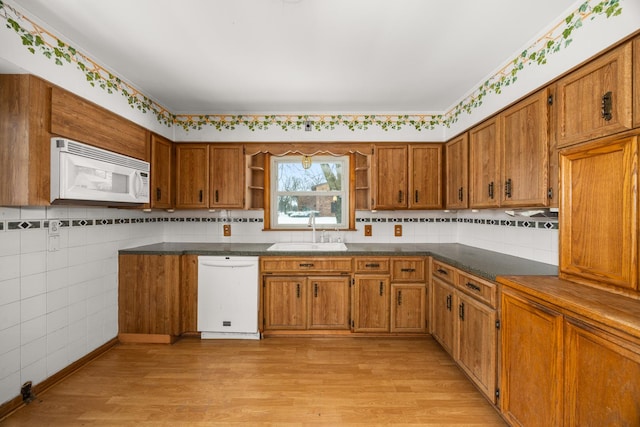 kitchen featuring white appliances, sink, decorative backsplash, and light wood-type flooring