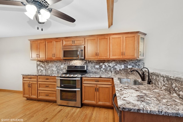 kitchen featuring tasteful backsplash, stainless steel appliances, light stone countertops, and sink