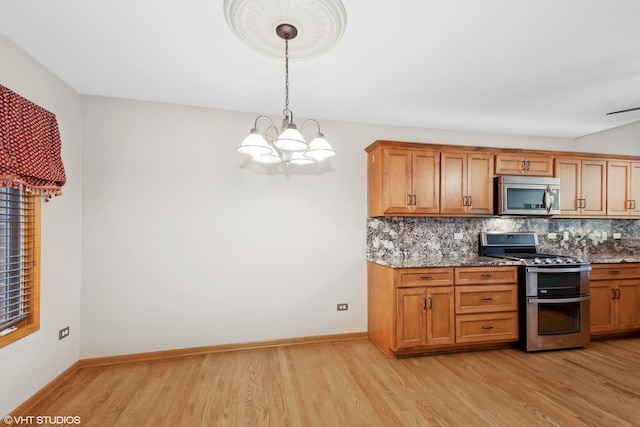 kitchen with light hardwood / wood-style flooring, appliances with stainless steel finishes, an inviting chandelier, hanging light fixtures, and backsplash