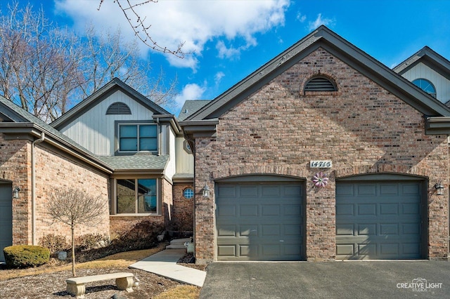 view of front of property with an attached garage, driveway, a shingled roof, and brick siding