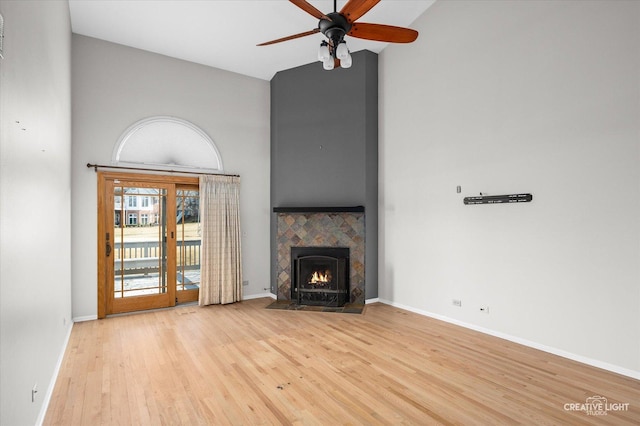 unfurnished living room featuring a fireplace, a ceiling fan, wood finished floors, high vaulted ceiling, and baseboards