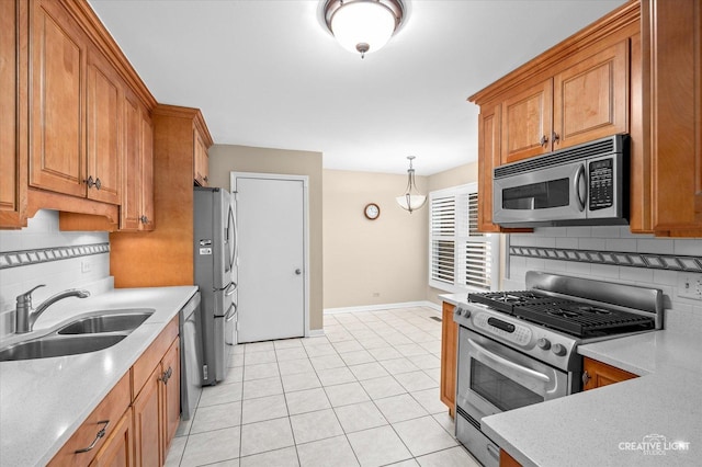 kitchen featuring stainless steel appliances, brown cabinetry, a sink, and decorative backsplash