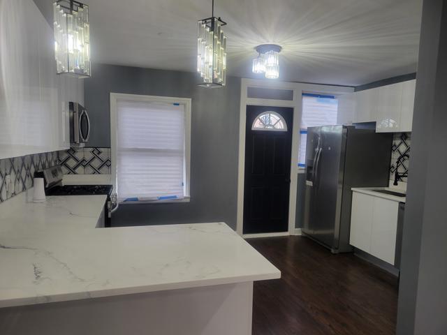 kitchen with hanging light fixtures, light stone countertops, white cabinets, and appliances with stainless steel finishes