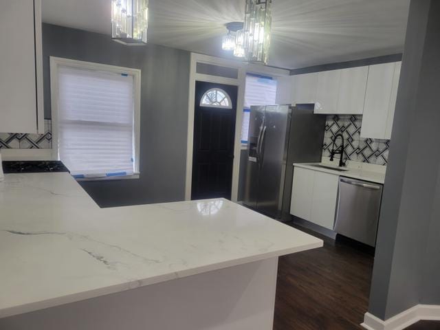 kitchen with pendant lighting, white cabinetry, stainless steel appliances, and a notable chandelier