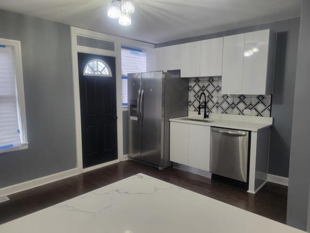 kitchen featuring stainless steel appliances, white cabinetry, light stone countertops, and sink