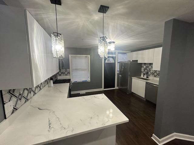 kitchen featuring sink, appliances with stainless steel finishes, white cabinetry, hanging light fixtures, and kitchen peninsula