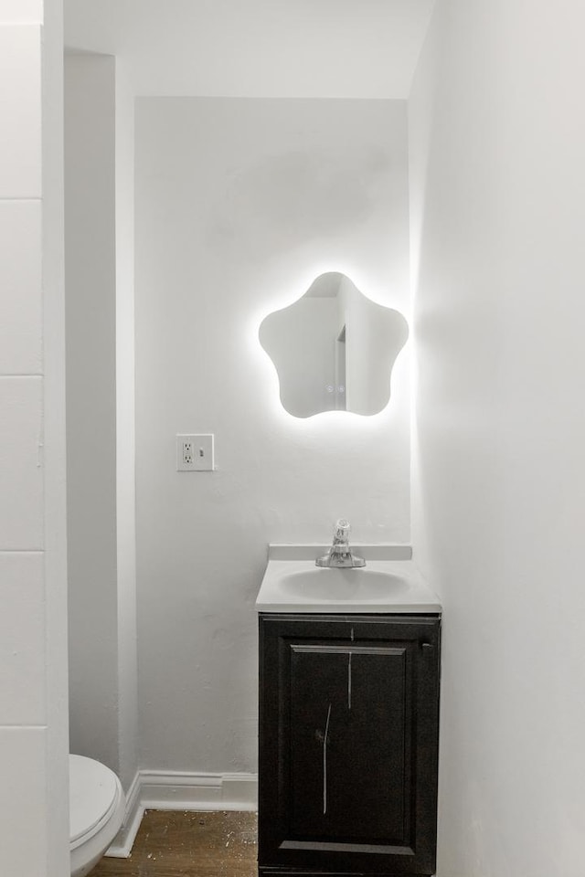 bathroom with hardwood / wood-style flooring, vanity, and toilet