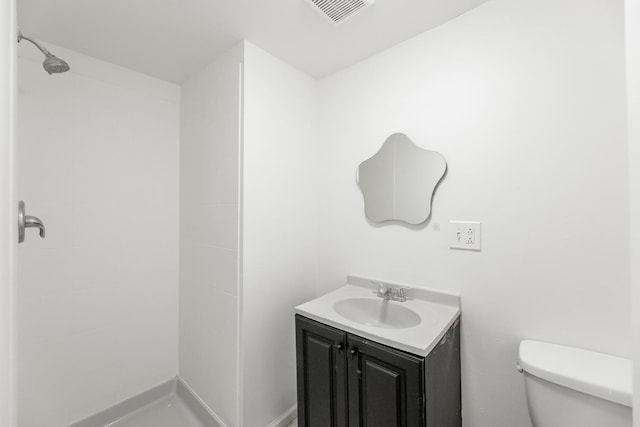 bathroom with vanity, a tile shower, and toilet