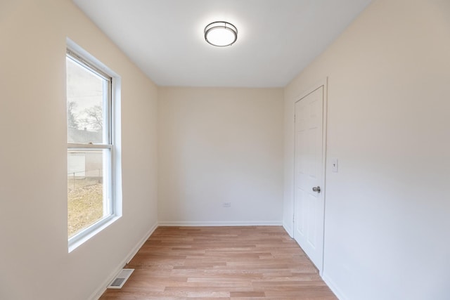 empty room with a wealth of natural light and light hardwood / wood-style floors