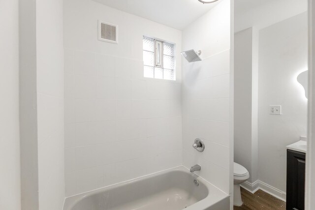 full bathroom with vanity, tiled shower / bath, hardwood / wood-style floors, and toilet