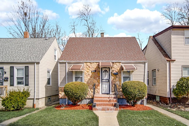 view of front of house with stone siding, a chimney, a front yard, and a shingled roof