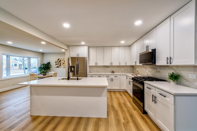 kitchen featuring stainless steel refrigerator with ice dispenser, tasteful backsplash, black range with gas stovetop, light hardwood / wood-style floors, and white cabinets