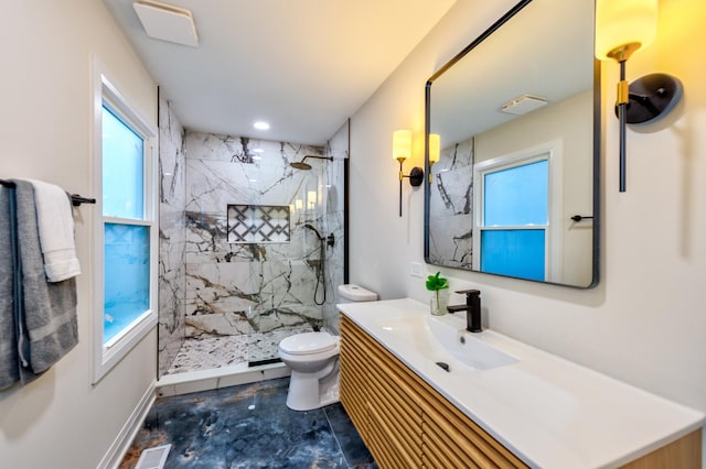 bathroom featuring vanity, a tile shower, and toilet