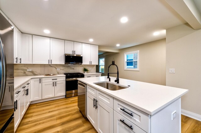 kitchen featuring white cabinets, appliances with stainless steel finishes, sink, and a kitchen island with sink