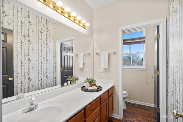 full bath with visible vents, toilet, vanity, wood finished floors, and baseboards