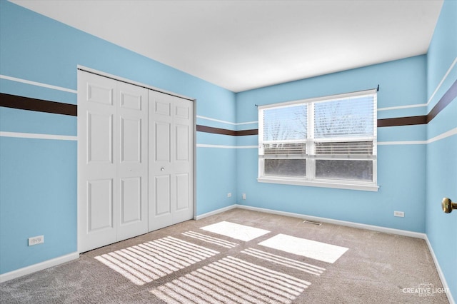 unfurnished bedroom featuring carpet floors, a closet, visible vents, and baseboards