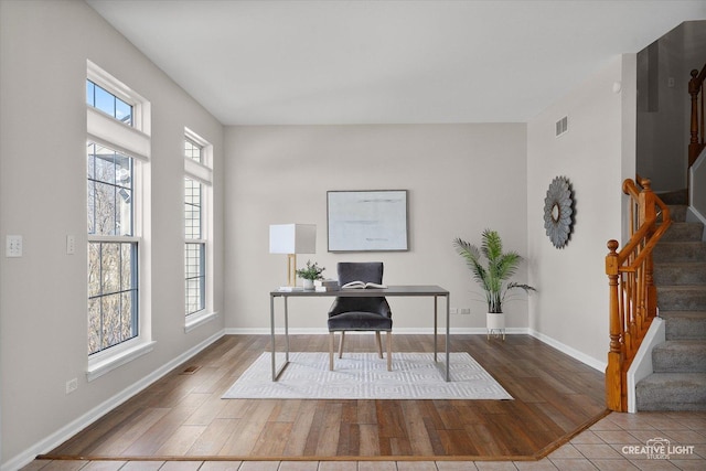 office space featuring baseboards, visible vents, and wood finished floors