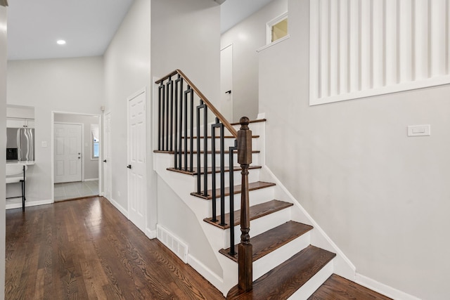 stairs featuring wood-type flooring and a high ceiling