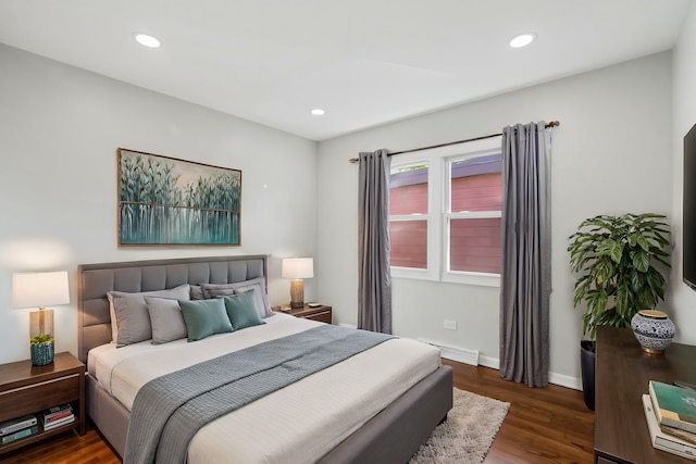 bedroom with dark wood-type flooring and a baseboard heating unit