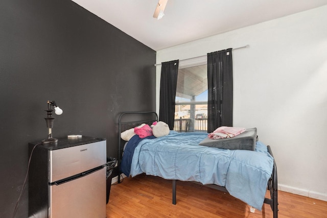 bedroom featuring stainless steel fridge, ceiling fan, and light hardwood / wood-style flooring