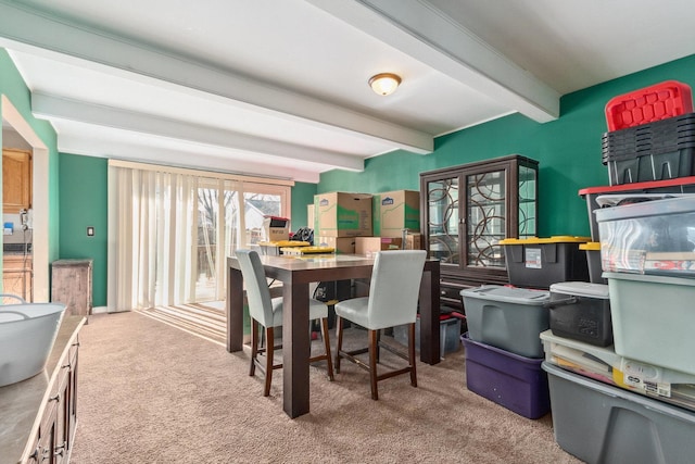 carpeted dining space with beamed ceiling