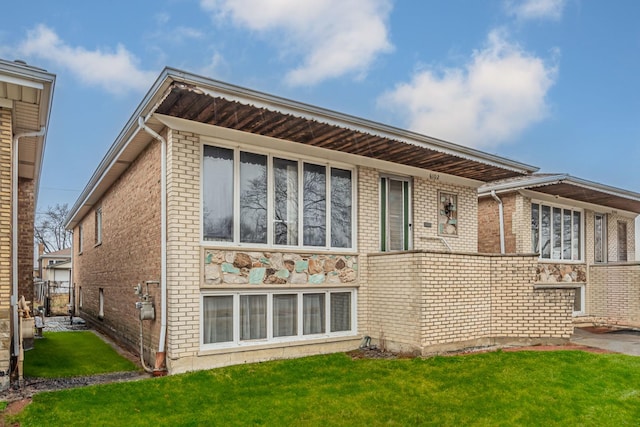 back of property with brick siding and a yard