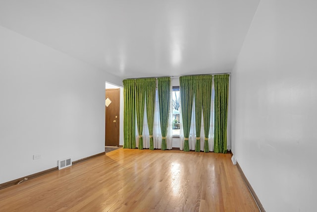 unfurnished room featuring visible vents, baseboards, and wood finished floors