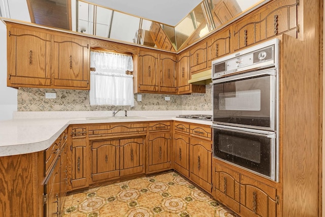 6102 W 64th St, Chicago, IL 60638 - kitchen featuring double oven, gas cooktop, under cabinet range hood, a sink, and brown cabinetry