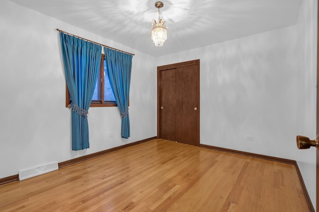 6102 W 64th St, Chicago, IL 60638 - empty room featuring a chandelier, wood finished floors, visible vents, and baseboards