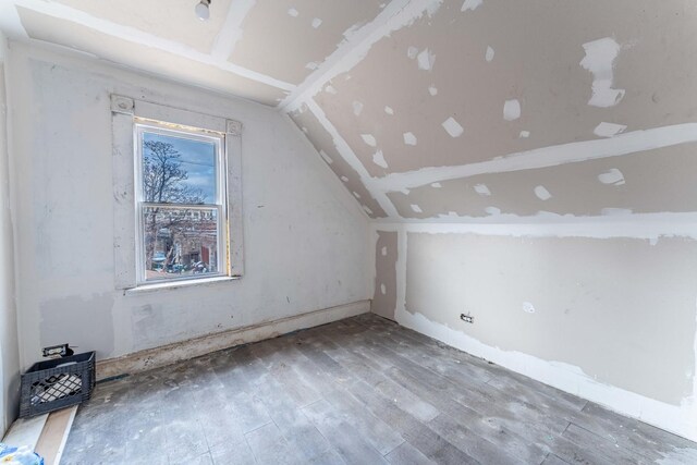 bonus room with wood-type flooring and vaulted ceiling