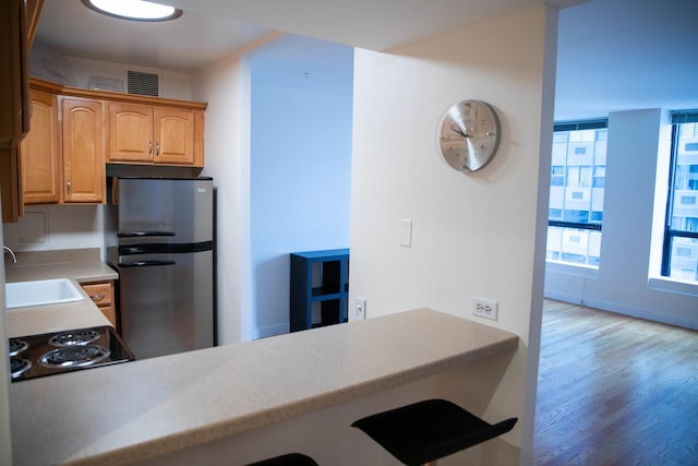 kitchen featuring hardwood / wood-style flooring, sink, stainless steel fridge, and black electric cooktop