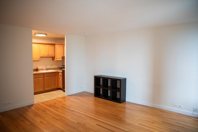 unfurnished living room with sink and light hardwood / wood-style floors